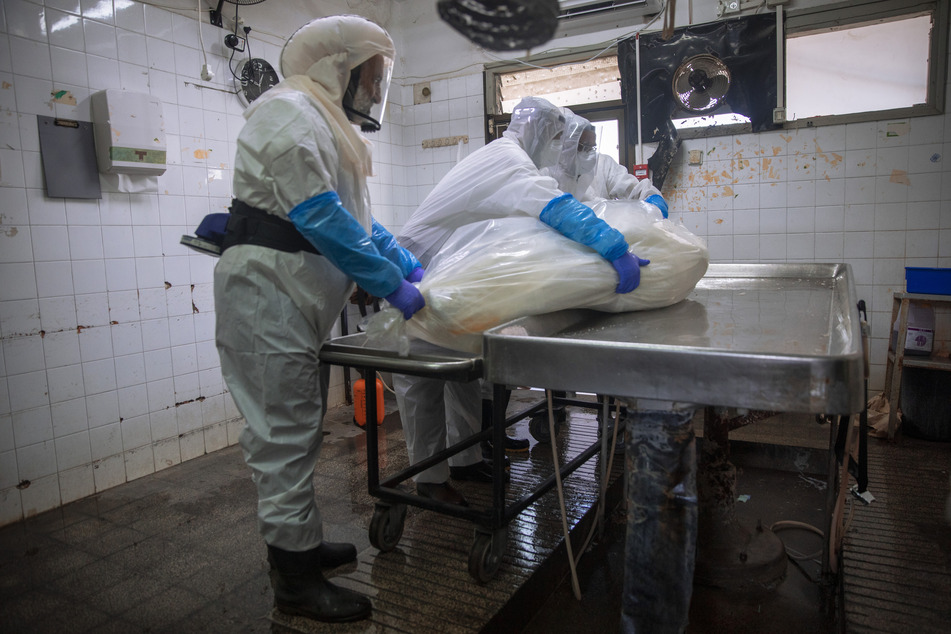 Infolge der auf einen Rekordwert angestiegenen Corona-Neuinfektionen in Israel sehen sich Bestattungshelfer mit einer wachsenden Anzahl von Covid-19-Todesopfern konfrontiert und müssen bei der Arbeit strenge Sicherheitsmaßnahmen einhalten.