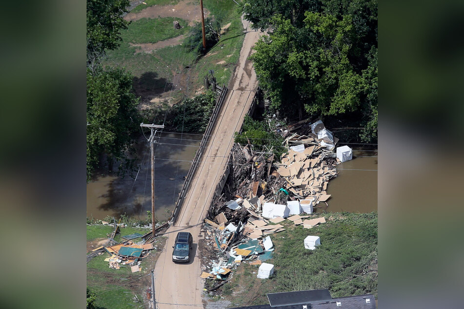 Ein Auto fährt im Osten Kentuckys über eine Brücke, neben der zahlreiche Trümmer liegen.