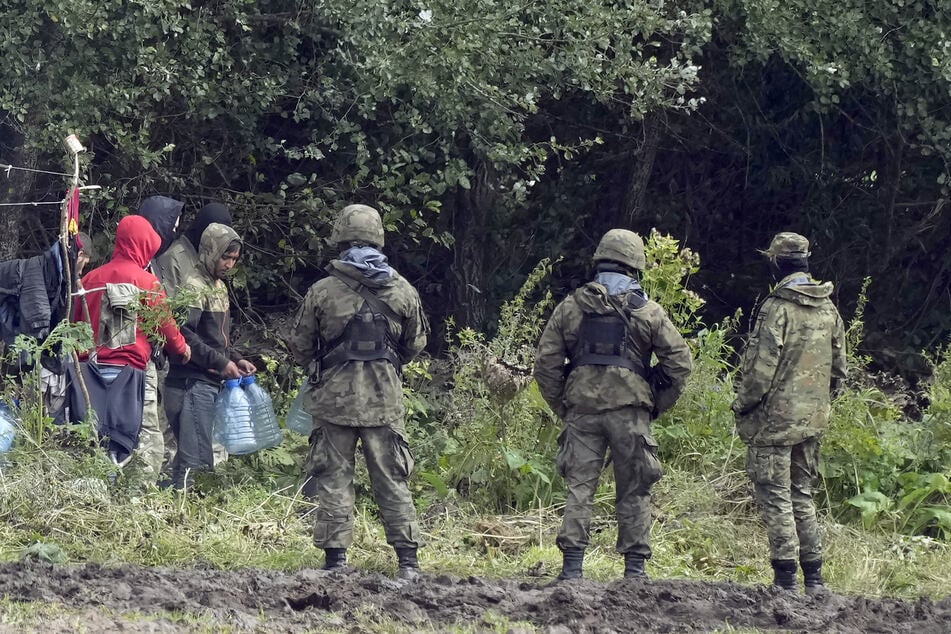 Mitglieder des polnischen Militärs treffen an der polnisch-belarussischen Grenze auf Migranten.