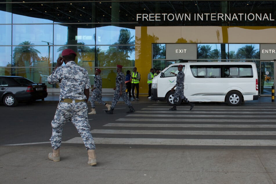 Security escort migrants in a National Public Health Agency (NPHA) after their arrival at Freetown International Airport, formerly known as Lungi International Airport, in Lungi on Wednesday.