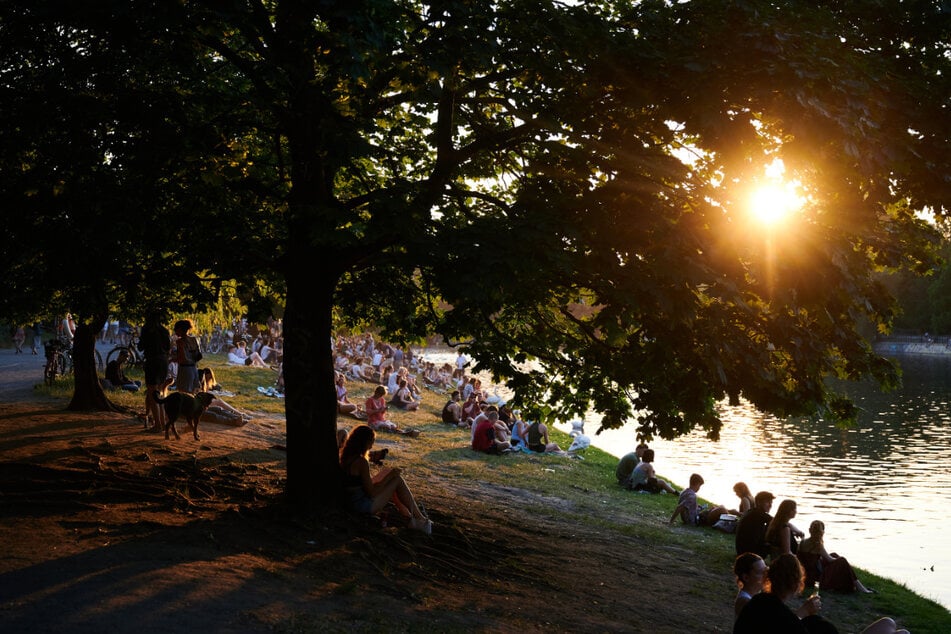 Viele Menschen sitzen bei sehr warmem Wetter in der Abendsonne am Ufer des Landwehrkanales.