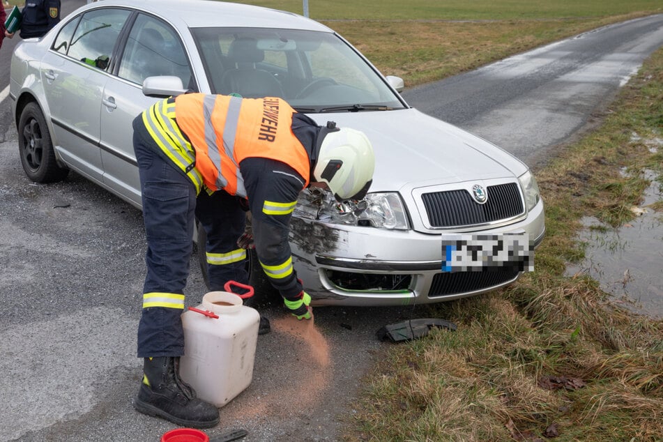 Ein Feuerwehrmann bindet Betriebsstoffe des verunfallten Škoda.