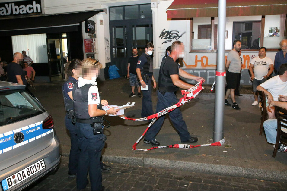 Polizisten sperren den Bereich vor dem Lokal in Berlin-Neukölln mit Flatterband ab.