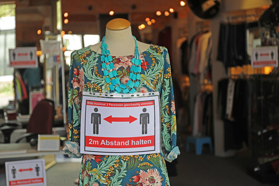 Im Eingang eines Modegeschäftes hängt als Hinweis an die Kunden ein Schild, das auf Abstandsregeln hinweist.