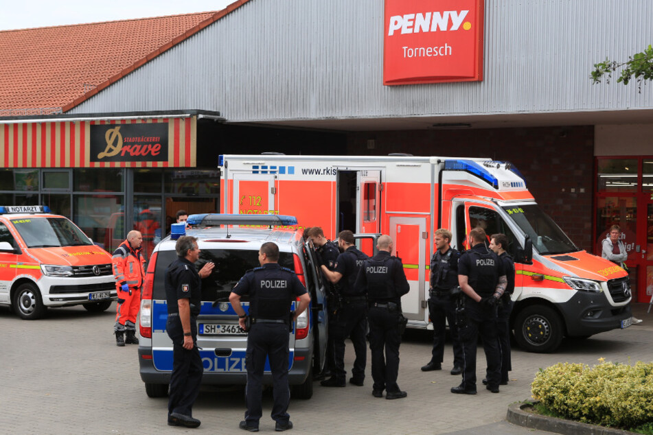 Einsatzkräfte stehen vor dem Penny-Markt in Tornesch.