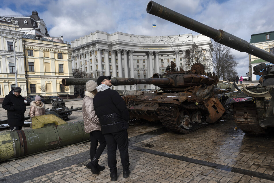Menschen betrachten zerstörte russische Panzer und gepanzerte Fahrzeuge, die in der Nähe der St. Michaels-Kathedrale in der Innenstadt ausgestellt sind.