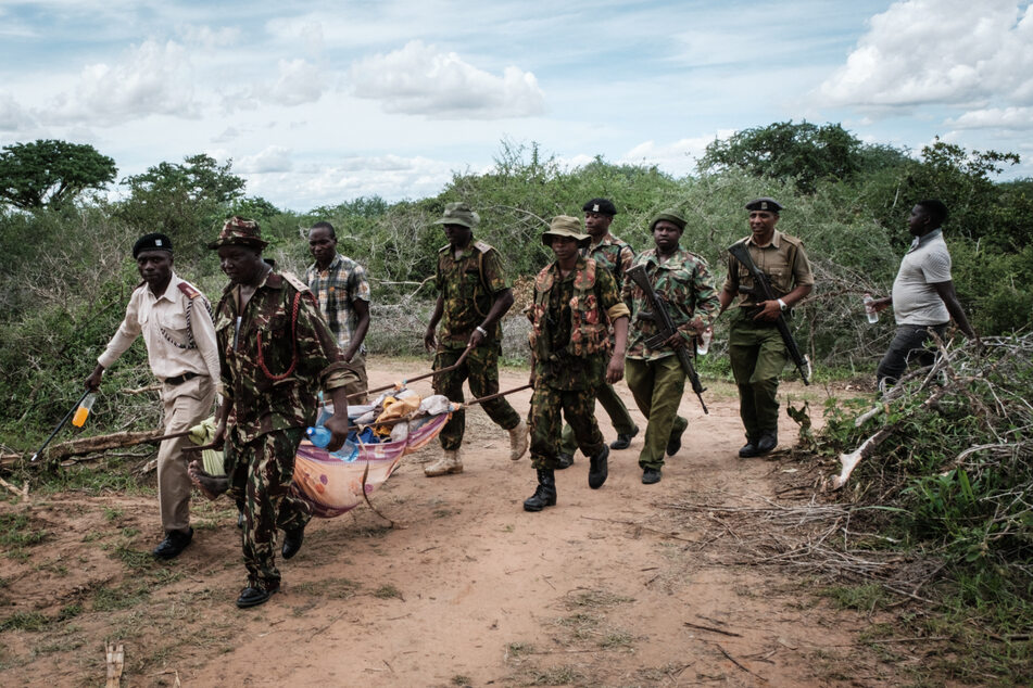 Kenianische Soldaten tragen einen entkräfteten Mann aus dem Sekten-Wald.