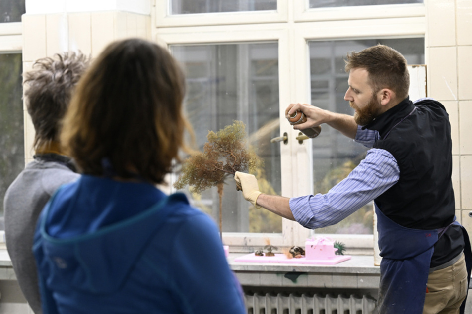 Martin Königsdorfer (r.) zeigt Kursteilnehmern des Botanikkurses der Krippenbauschule an der Schule für Holz und Gestaltung, wie man die zuvor gefertigten Gewächse einfärbt.