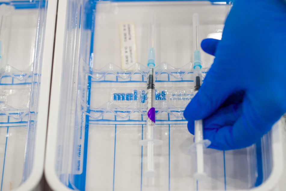 Eine medizinische Fachkraft legt im Nürnberger Impfzentrum auf dem Messegelände eine aufbereitete Impfspritze mit dem Pfizer-BioNTech-COVID-19-Impfstoff in eine Schale.
