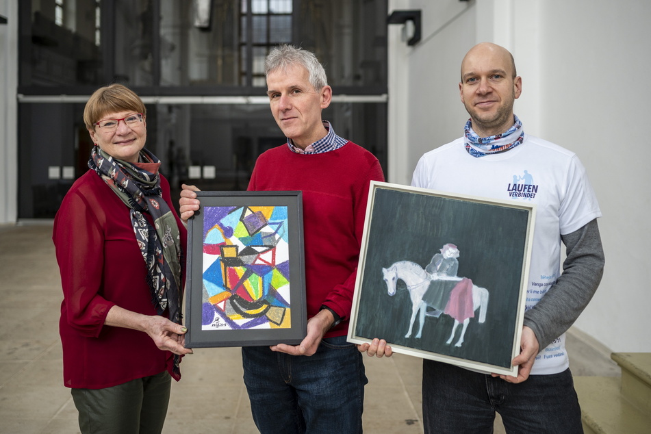 Jana Pinka (59, Linke, v.l.) , Stefan Benkert (58) und Max Knuth (39) vom Verein "Freiberg für alle" mit zwei Bildern der Aktion "Kunst verschenken – Jaden unterstützen".