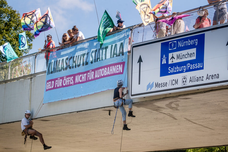 Klimaaktivisten der Extinction Rebellion München seilen sich über dem Georg-Brauchle-Weg über der Fahrbahn ab.