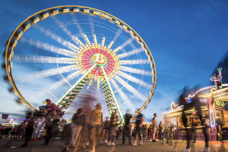 Besucher genießen 2019 zur blauen Stunde das 81. Stuttgarter Frühlingsfest auf dem Cannstatter Wasen. Diesen Frühling wird es wieder ausfallen.