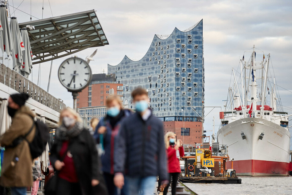 Passanten tragen an den Landungsbrücken Masken.