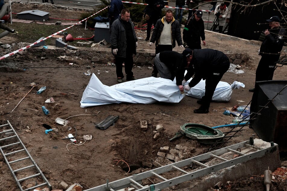 Authorities cover up the bodies of civilians discovered in a mass grave near Kyiv.