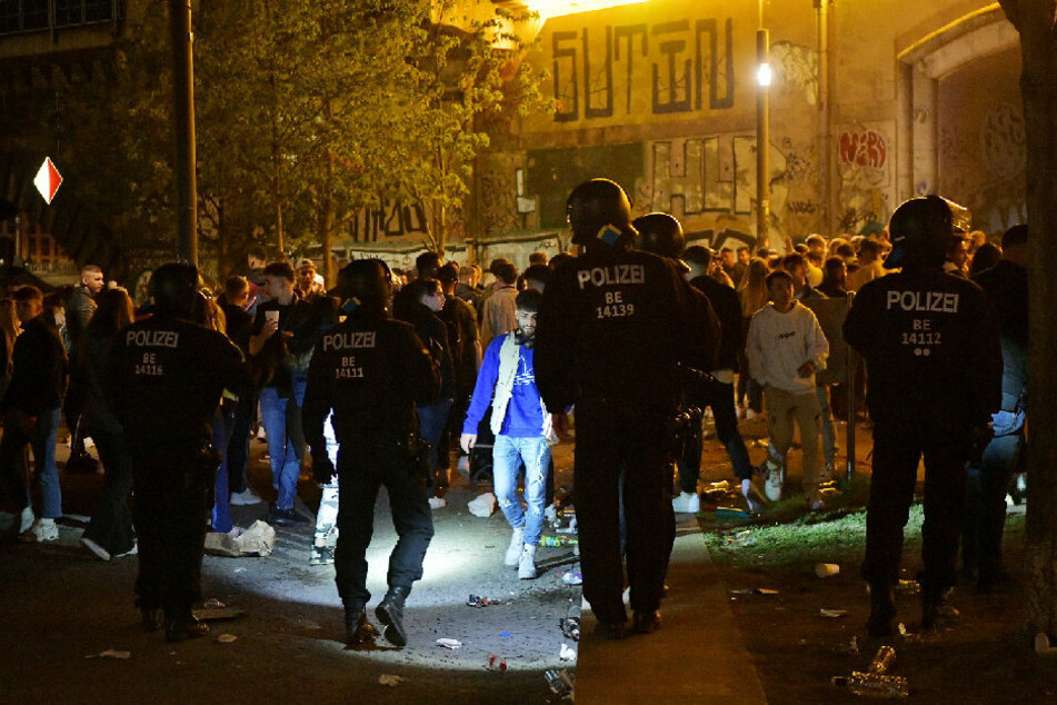 Polizisten und hauptsächlich jugendliche Feiernde stehen sich im James-Simon-Park gegenüber.