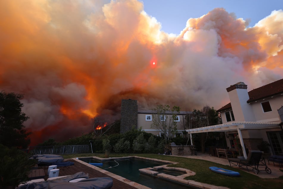 A brush fire burns near homes in Pacific Palisades, California, on Tuesday.