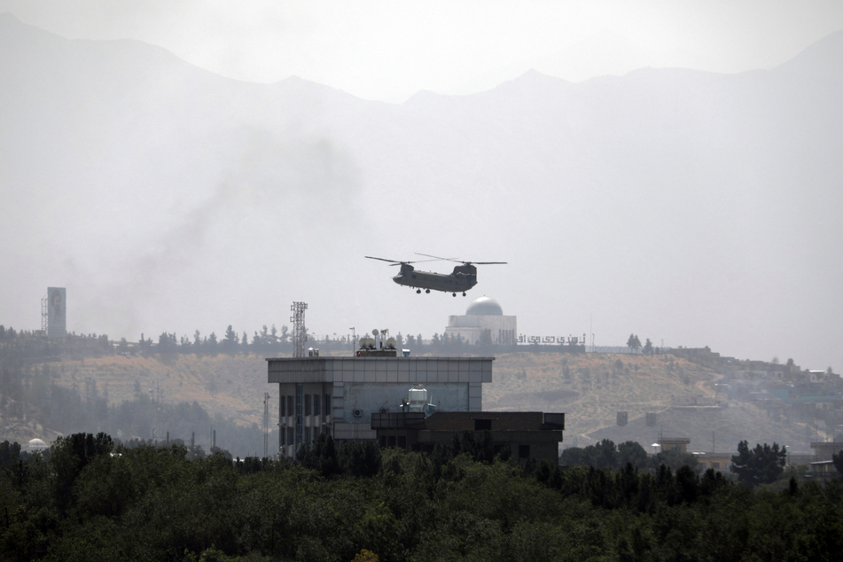 Ein Hubschrauber der USA vom Typ Chinook fliegt über der US-Botschaft in Kabul. Diplomatenfahrzeuge verlassen das Gelände, während die Taliban auf die afghanische Hauptstadt vorrücken.