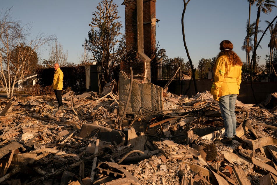 Residents stand on the remains of their home, which was destroyed by the Palisades Fire, in the Pacific Palisades neighborhood in Los Angeles, California.