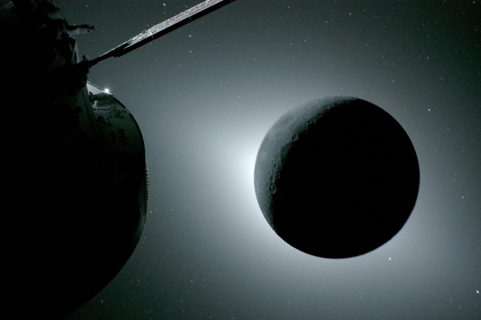 Sonnenfinsternis im All: Der Mond verdeckt die Sonne. Am linken Rand des Mondes reflektiert die Erde das Sonnenlicht und erhellt dort den Mond, während der Rest des Erdtrabanten völlig dunkel ist.