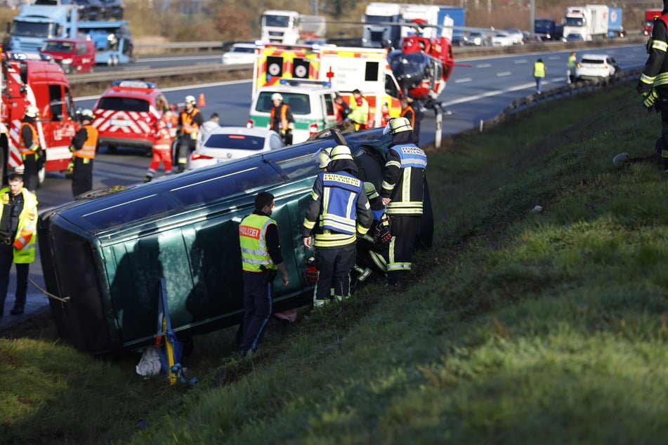 Einsatzkräfte stehen am Wrack des VW-Busses im Grünstreifen an der A3.