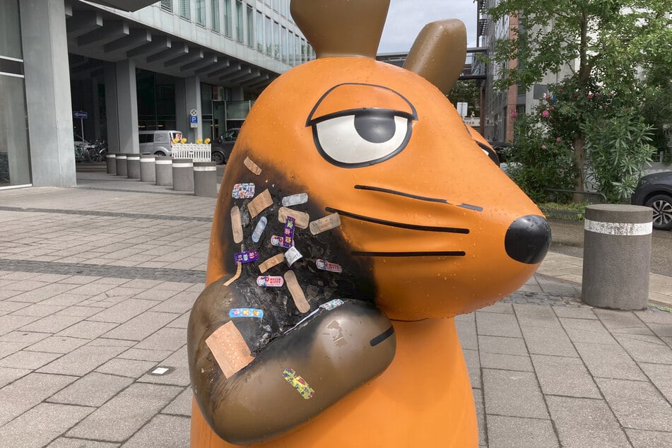 Passanten haben die ramponierte Statue der Maus mit bunten Pflastern beklebt.