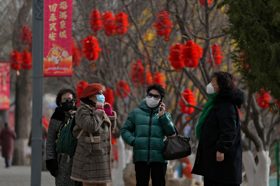 Frauen mit Mund-Nasen-Schutz besuchen einen öffentlichen Park, der mit Dekorationen zum chinesischen Neujahrsfest geschmückt ist.