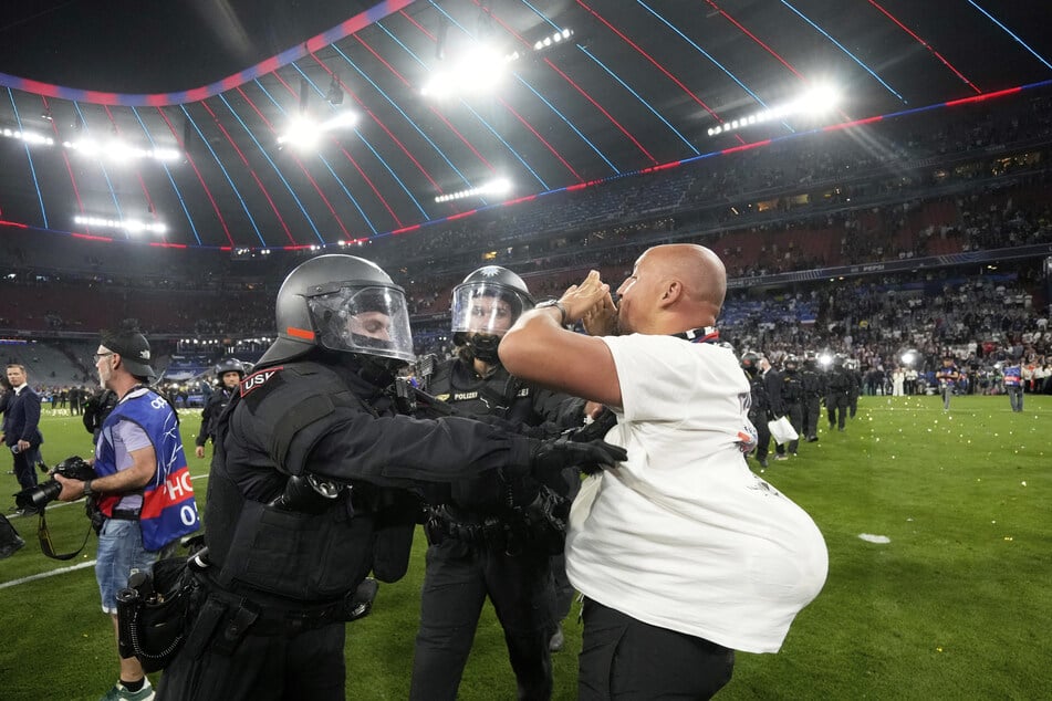 Polizisten verhindern, dass die PSG-Fans weiter über den Rasen in der Allianz Arena stürmen.