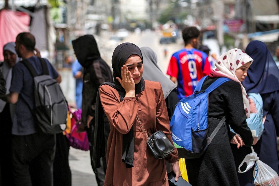 A Palestinian woman reacts as she waits with others before being displaced from Rafah in the southern Gaza Strip.