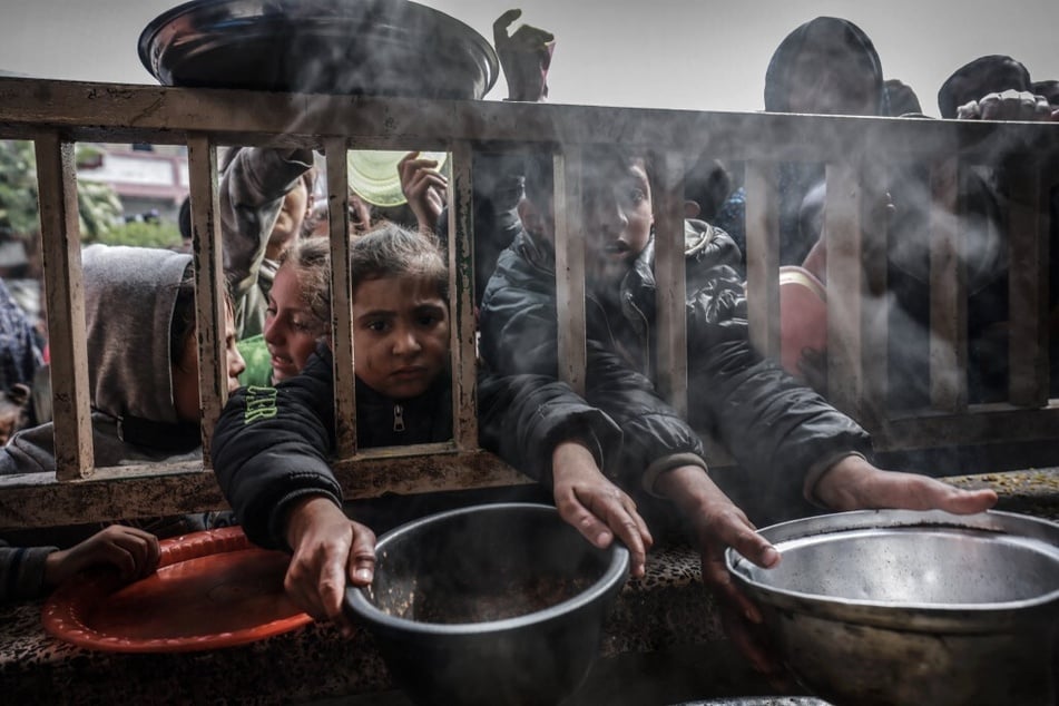 Forcibly displaced Palestinian children gather to receive food at a government school in Rafah in the southern Gaza Strip.