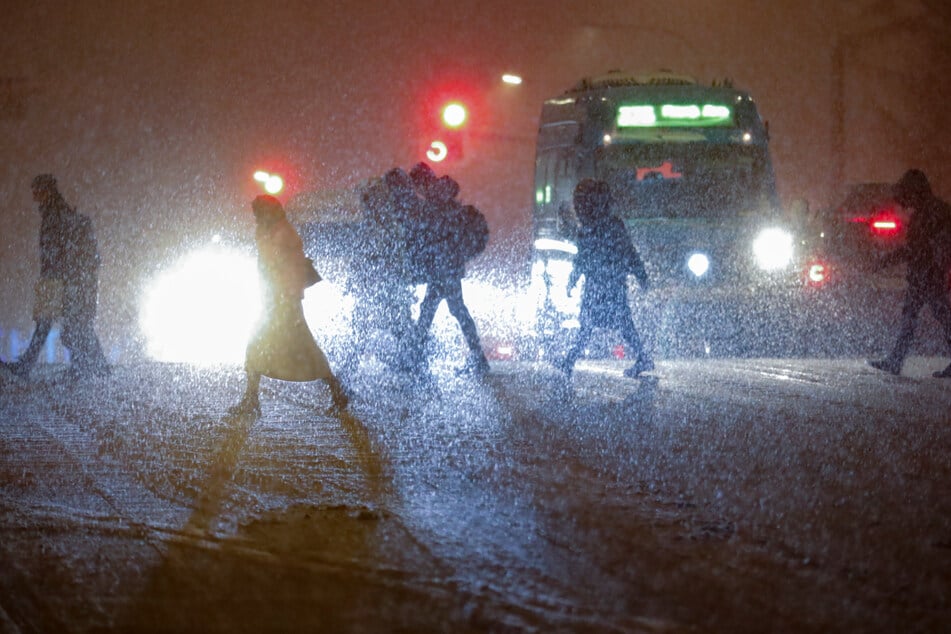 Moskau: Fußgänger überqueren eine Straße während es schneit.