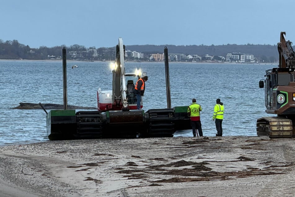 Der Schwinmbagger steht am Wasser, daneben ein Schaufelbagger. Auch eine Planierraupe und ein weiterer Bagger stehen bereit
