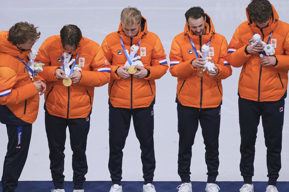 Die niederländischen Shorttrack-Herren begutachten interessiert ihre Goldmedaillen über die 5000-Meter-Distanz.