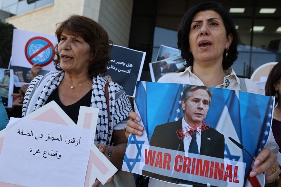 Palestinians representing civil organizations for women hold signs with an image of US Secretary of State Antony Blinken reading "War Criminal" during a protest outside the UN offices in the West Bank city of Ramallah.