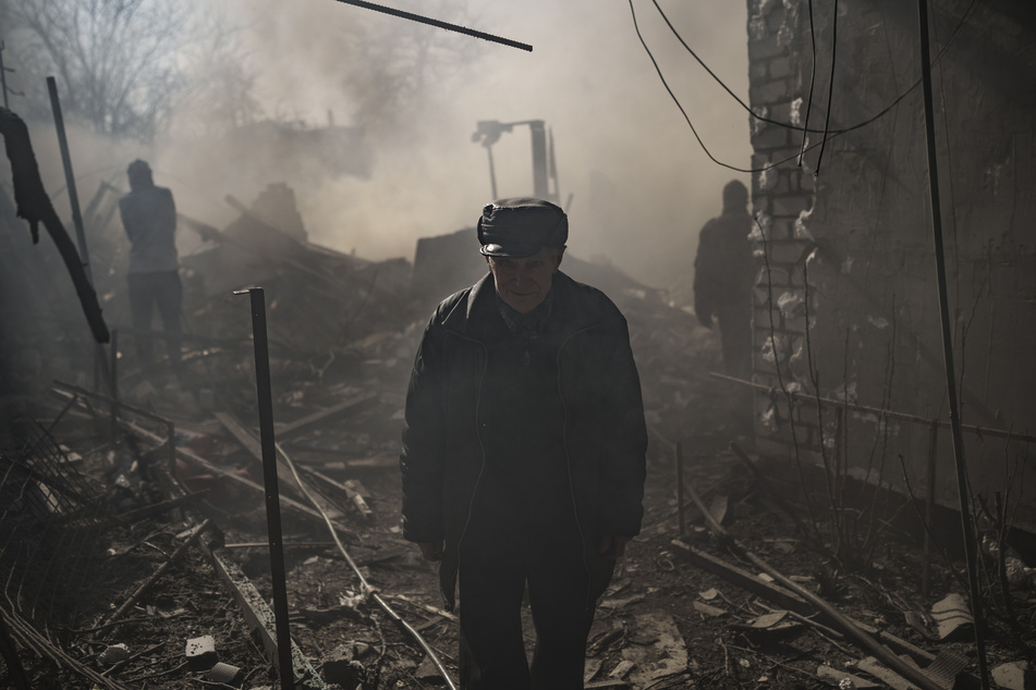 Menschen stehen inmitten von Trümmern zerstörter Wohnhäuser in Charkiw .