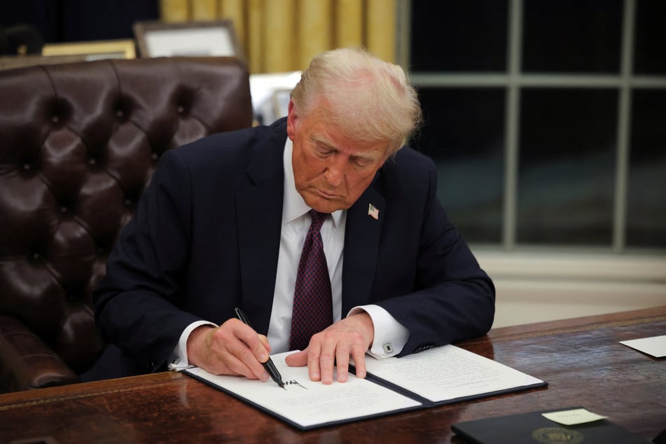 Newly inaugurated president Donald Trump signs executive orders in the Oval Office of the White House on January 20, 2025.