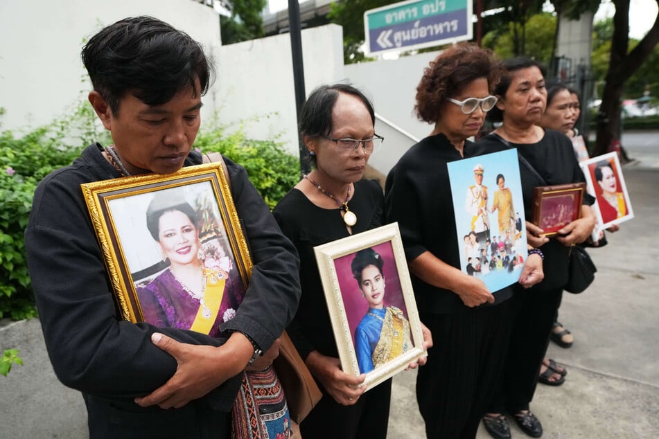 Thailänder halten Porträts der ehemaligen thailändischen Königin Sirikit in den Händen.