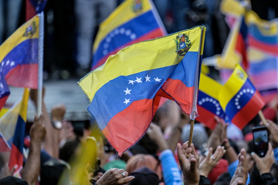 Venezuelans wave flags as they take part in a protest against the bounty on President Nicolas Maduro imposed by the Trump admnistration, in Caracas on August 11, 2025.