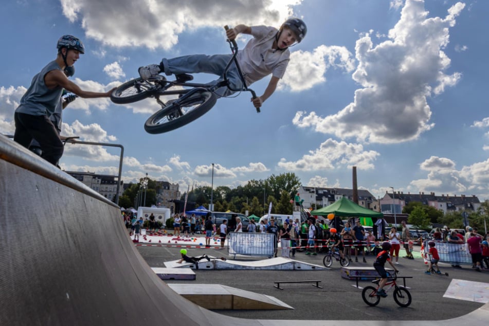 Hoch hinaus bei Sports United 2025: Ein BMX-Fahrer zeigt einen fetten Sprung, unten läuft das Mitmachfest weiter.