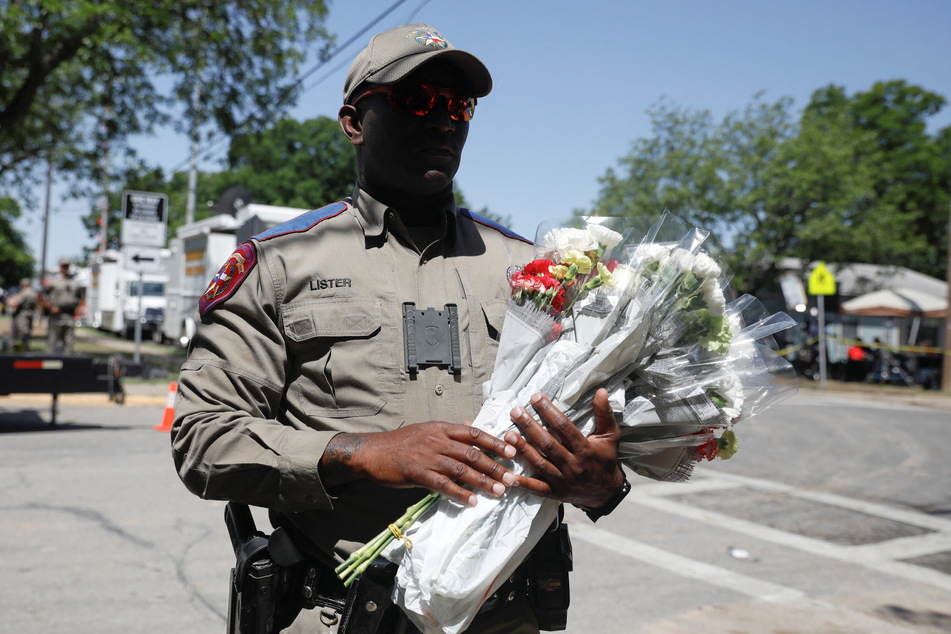 A Texas Public Safety officer held flowers that people brought to Robb Elementary School on Wednesday, the day after a gunman killed 19 children and two teachers at the school in Uvalde, Texas.