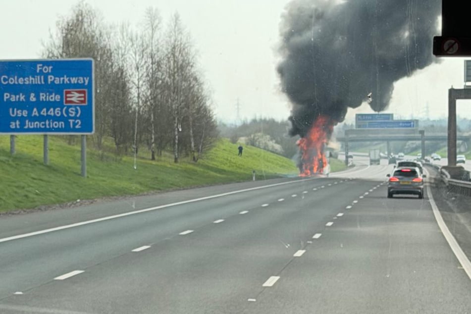 Dieses Foto zeigt den Fanbus in Vollbrand: Flammen greifen um sich, schwarzer Rauch zieht nach oben.