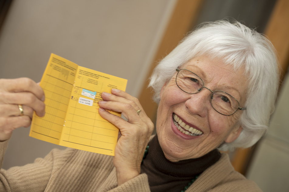 Seniorin Ursula Neuberger hält ihren Impfpass, in dem eine Grippe-Impfung (oben) und ihre erste Corona-Impfung vermerkt sind.