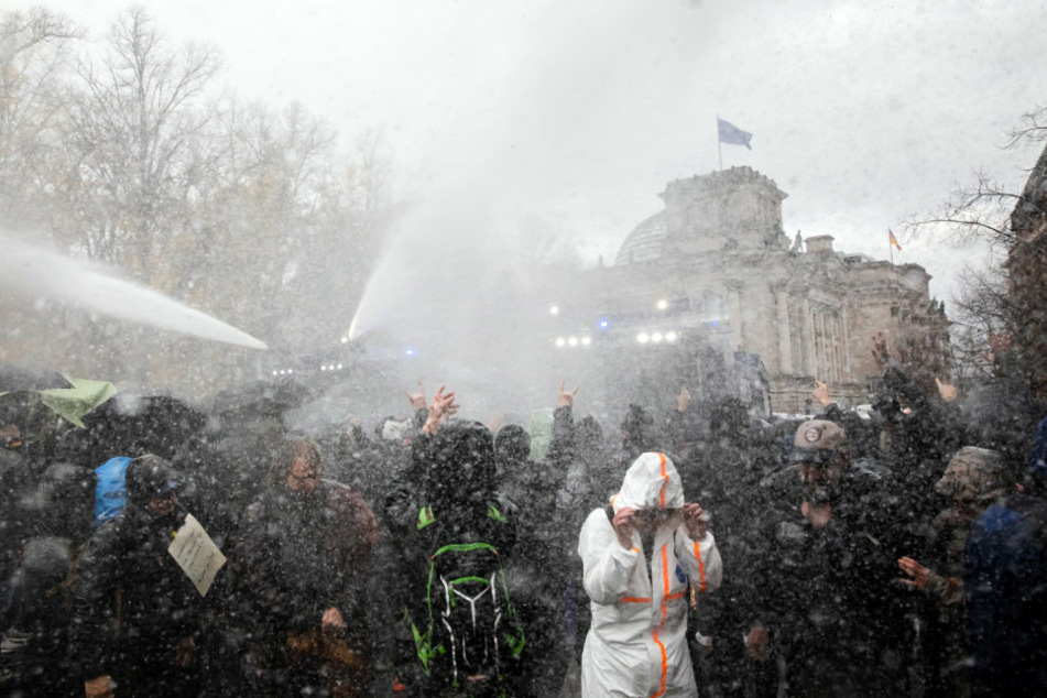 Die Polizei setzt bei einer Demonstration gegen die Corona-Einschränkungen der Bundesregierung am Brandenburger Tor unweit des Reichstagsgebäudes (hinten) Wasserwerfer ein.