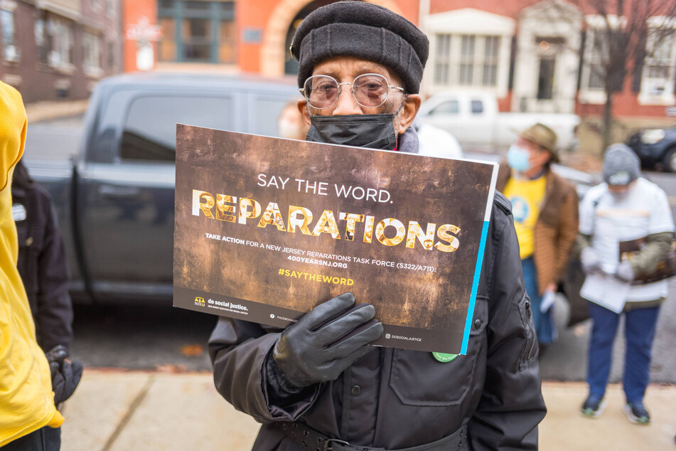 A protestor holds a sign calling for reparations at a demonstration outside the Statehouse Annex in Trenton, New Jersey, in December 2021.