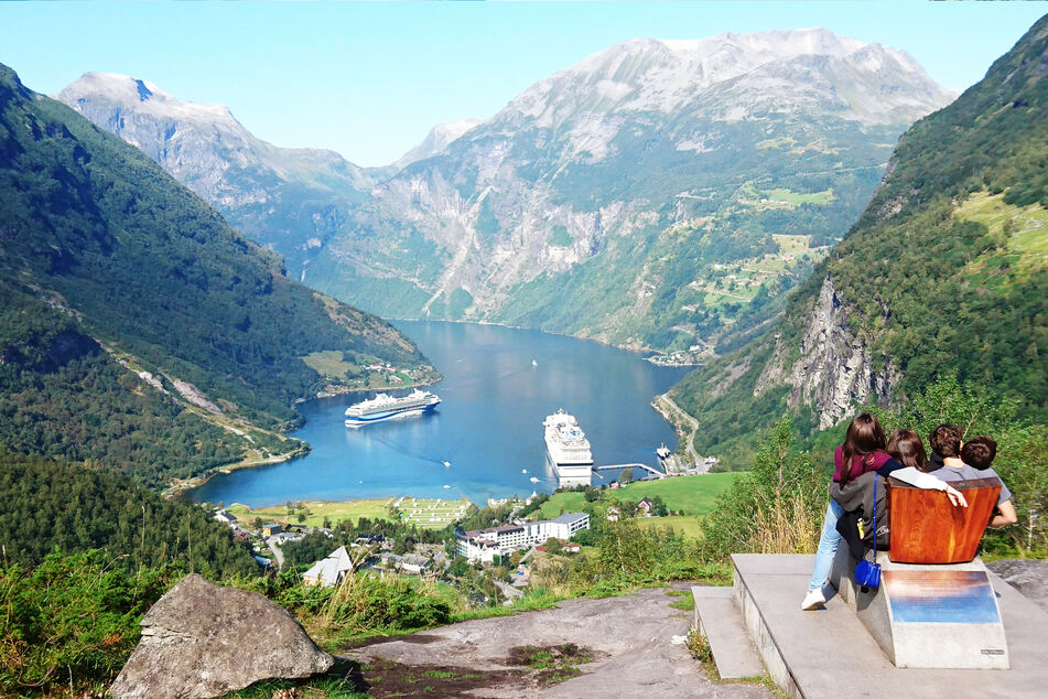 Personenen schauen runter in den Geirangerfjord im Südwesten Norwegens auf die dort liegenden Kreuzfahrtschiffe.