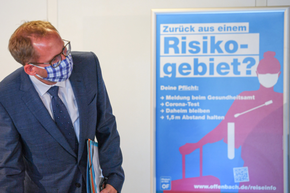 Kai Klose (Bündnis 90/Die Grünen), Sozialminister des Landes Hessen, steht am Freitag zu Beginn einer Pressekonferenz im Offenbacher Stadion neben einem Plakat mit der Aufschrift "Zurück aus einem Risikogebiet?".