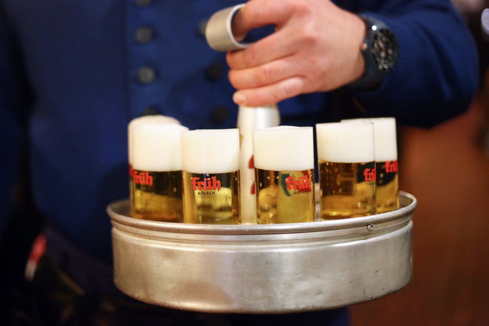 Ein Köbes (Kellner) trägt Kölsch-Bier der Brauerei Früh aus.