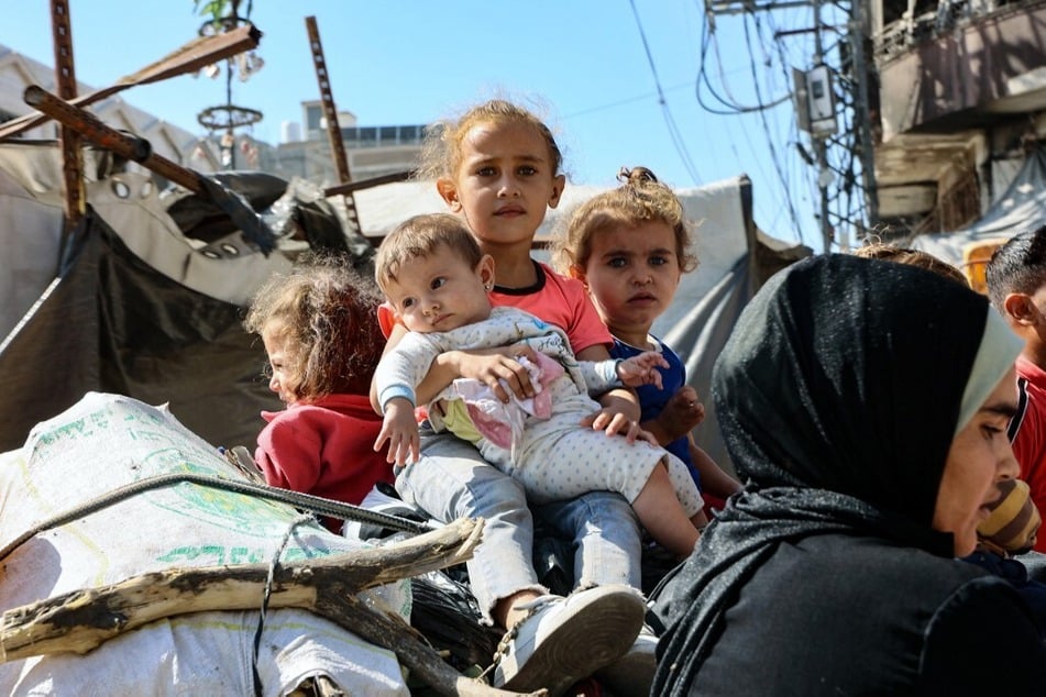 Palestinian children sit atop their family's belongings as they flee areas north of Gaza City on October 12, 2024.