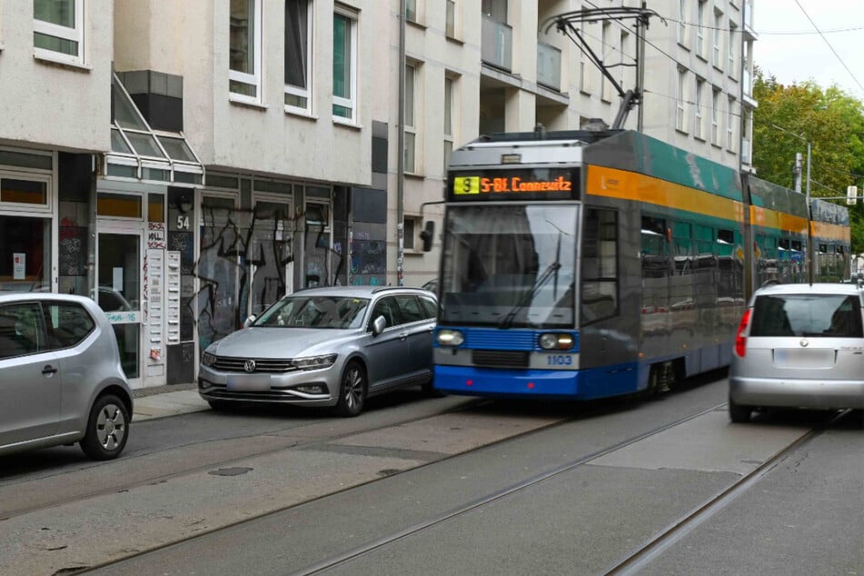 Man kann kaum hinschauen: Eine Straßenbahn fährt dicht an parkenden Autos vorbei.