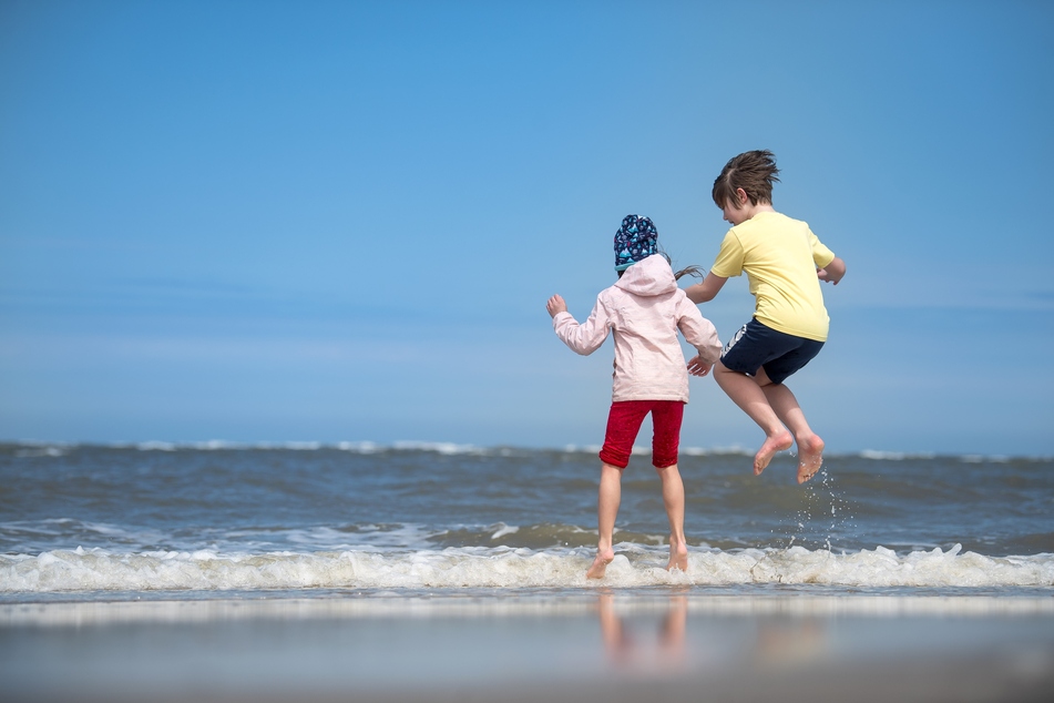 Zwei Kinder spielen am Strand.
