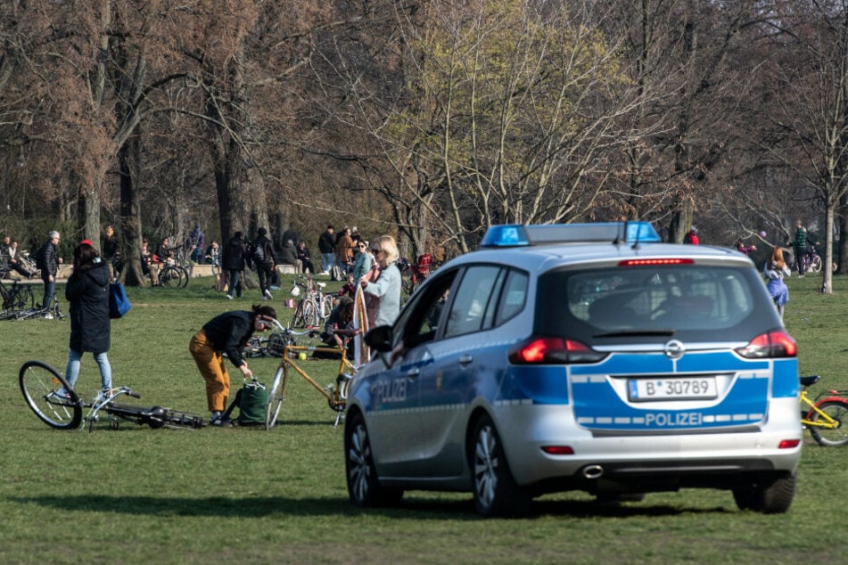 Eine Polizeistreife fährt durch den Treptower Park und fordert die Menschen auf, die Wiese zu verlassen.